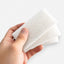 Two AquaFin polyester floss pads held in a hand