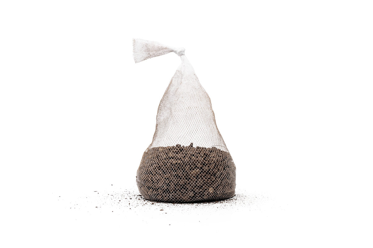 A single tied mesh bag of UNS Controbase sitting on loose granules