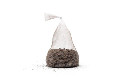 A single tied mesh bag of UNS Controbase sitting on loose granules