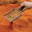 Exo Terra Stainless Steel Scooper sifting debris from terrarium sand substrate